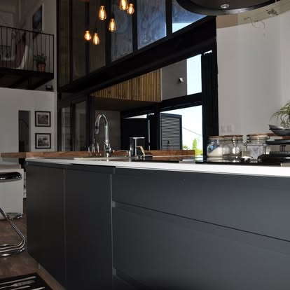 Cuisine noire sous mezzanine avec verrière noire et suspensions à filament, Saint-Paul